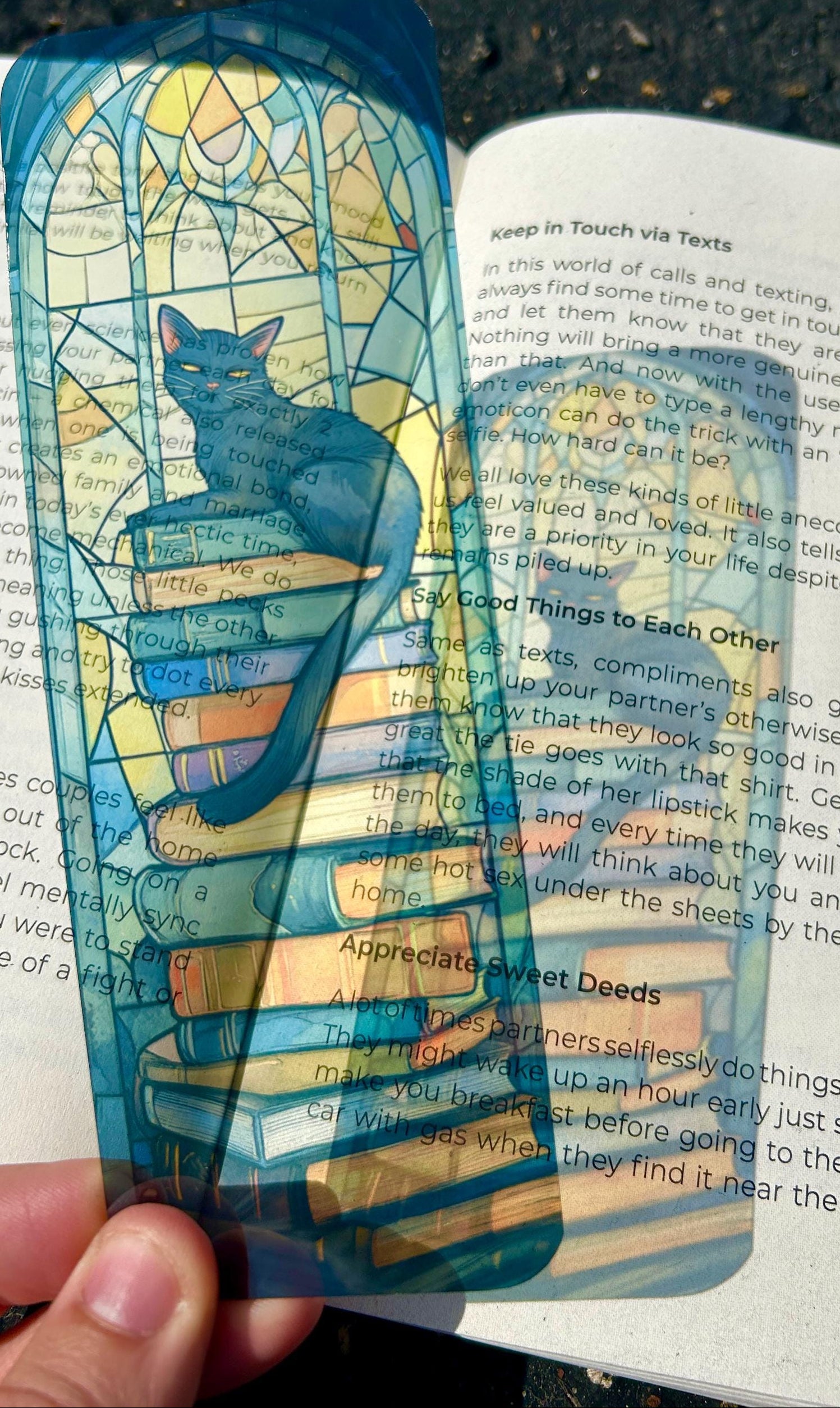 Stained glass-style bookmark with a cat design held over an open book.