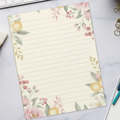Floral lined paper on a desk with a keyboard, coffee, and office supplies.