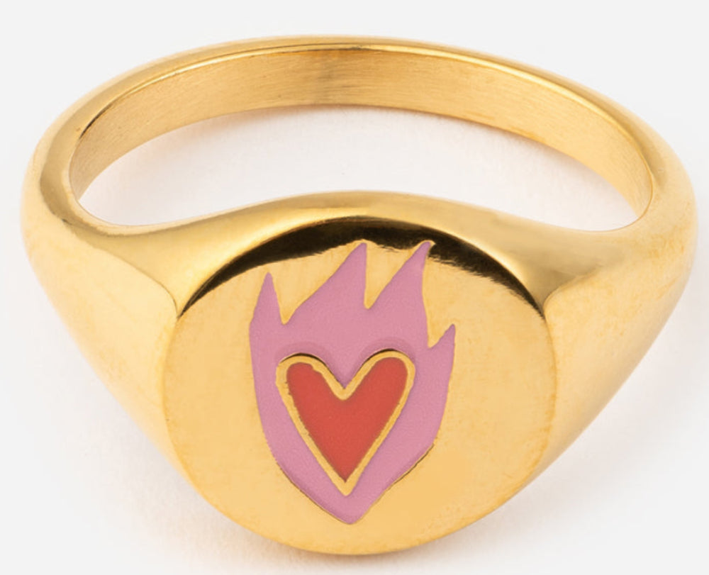 Gold ring with a heart and flame design on a white background