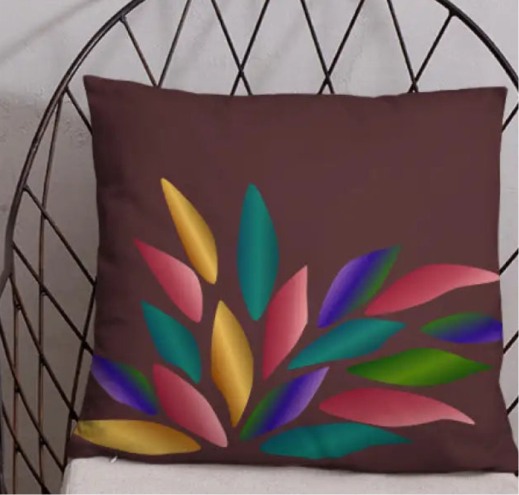 Decorative pillow with colorful leaf design on a wire chair against a light gray wall.