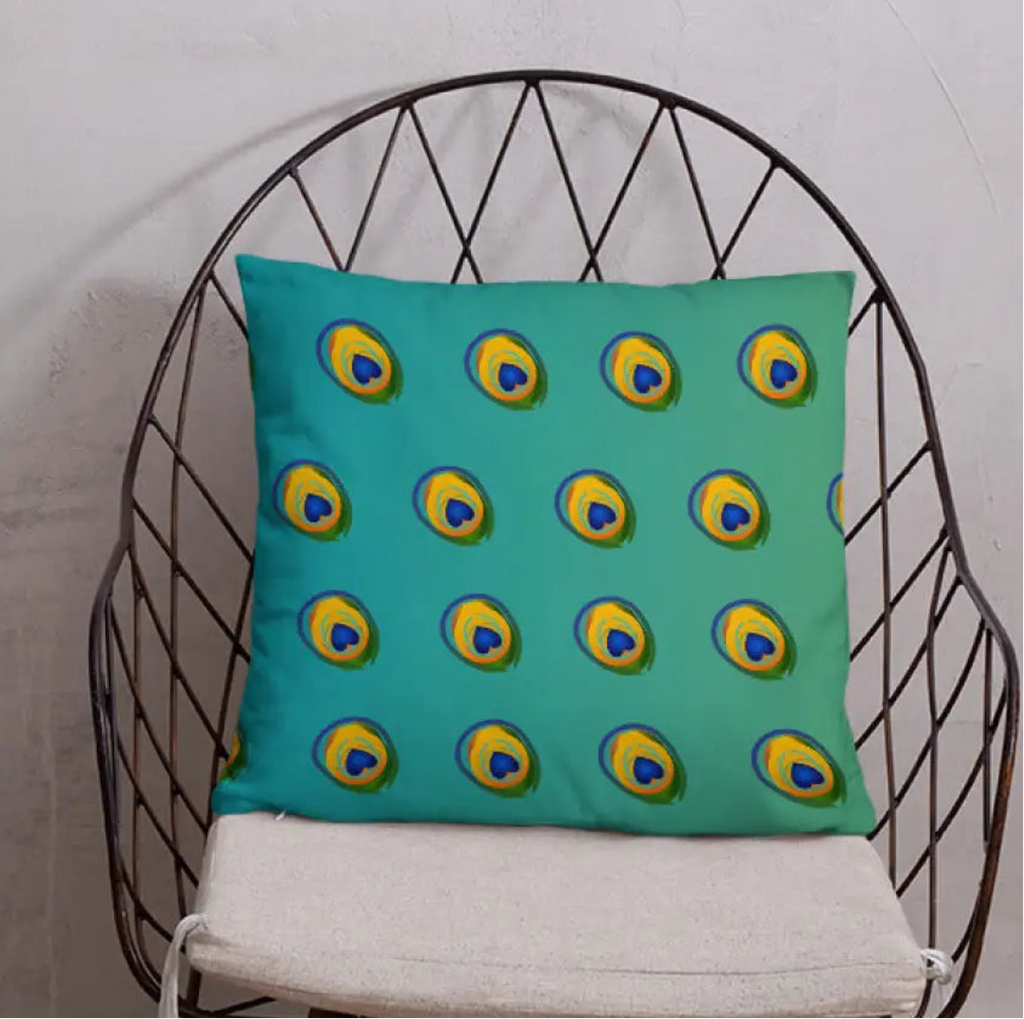 Teal pillow with peacock feather pattern on a black wire chair against a white wall.