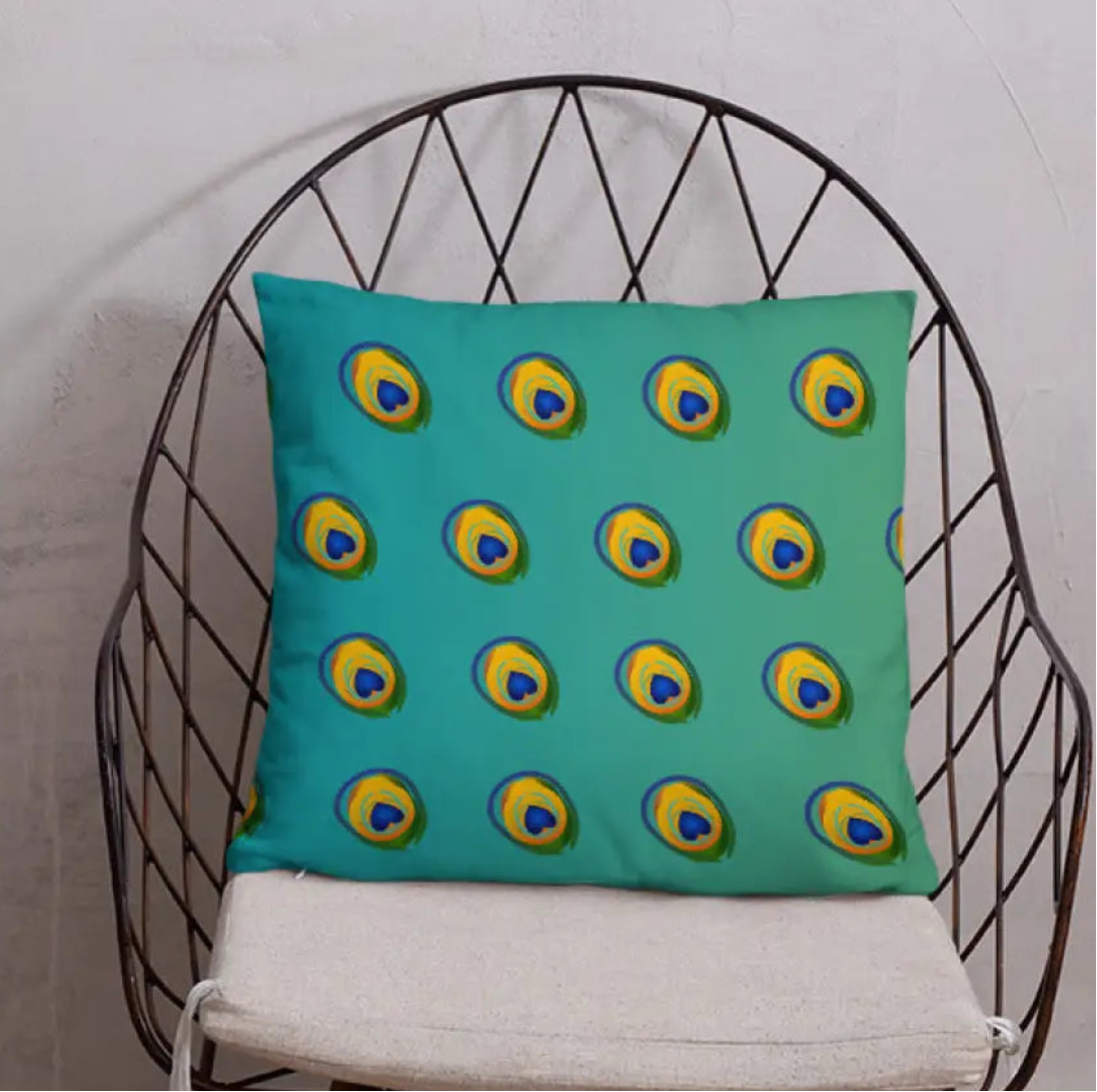 Teal pillow with peacock feather pattern on a black wire chair against a white wall.