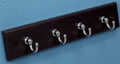 Black coat rack with five silver hooks on a white background