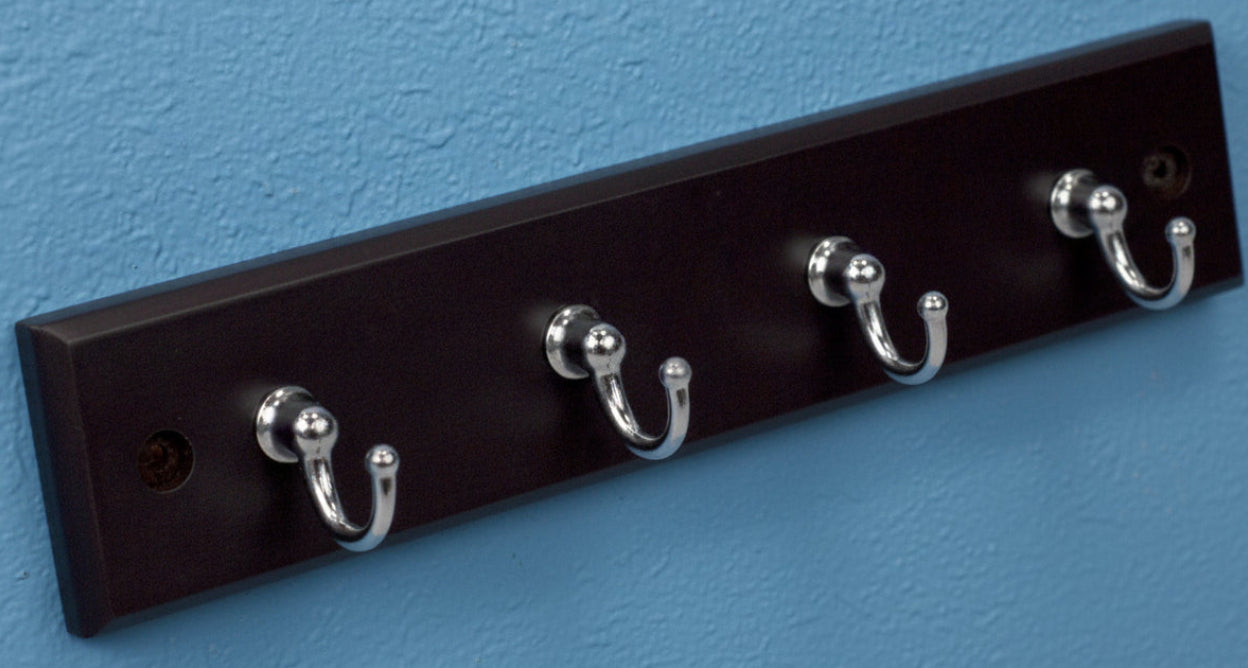 Black coat rack with five silver hooks on a white background