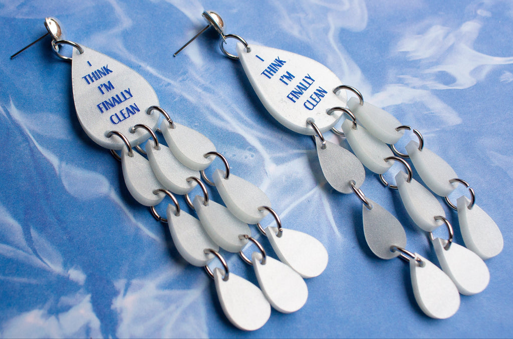 Pair of earrings with teardrop-shaped charms on a blue textured background