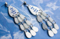 Pair of earrings with teardrop-shaped charms on a blue textured background