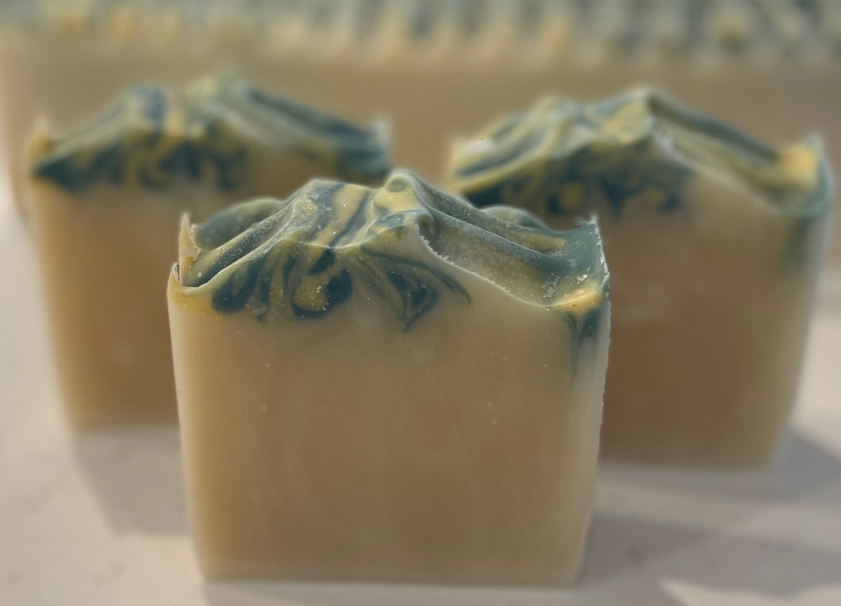 Three rectangular soap bars with green and white swirls on a marble surface.