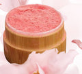 Pink cosmetic product on a wooden stand with cherry blossom petals in the background