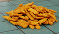 Pile of small, beige-colored snacks on a white background