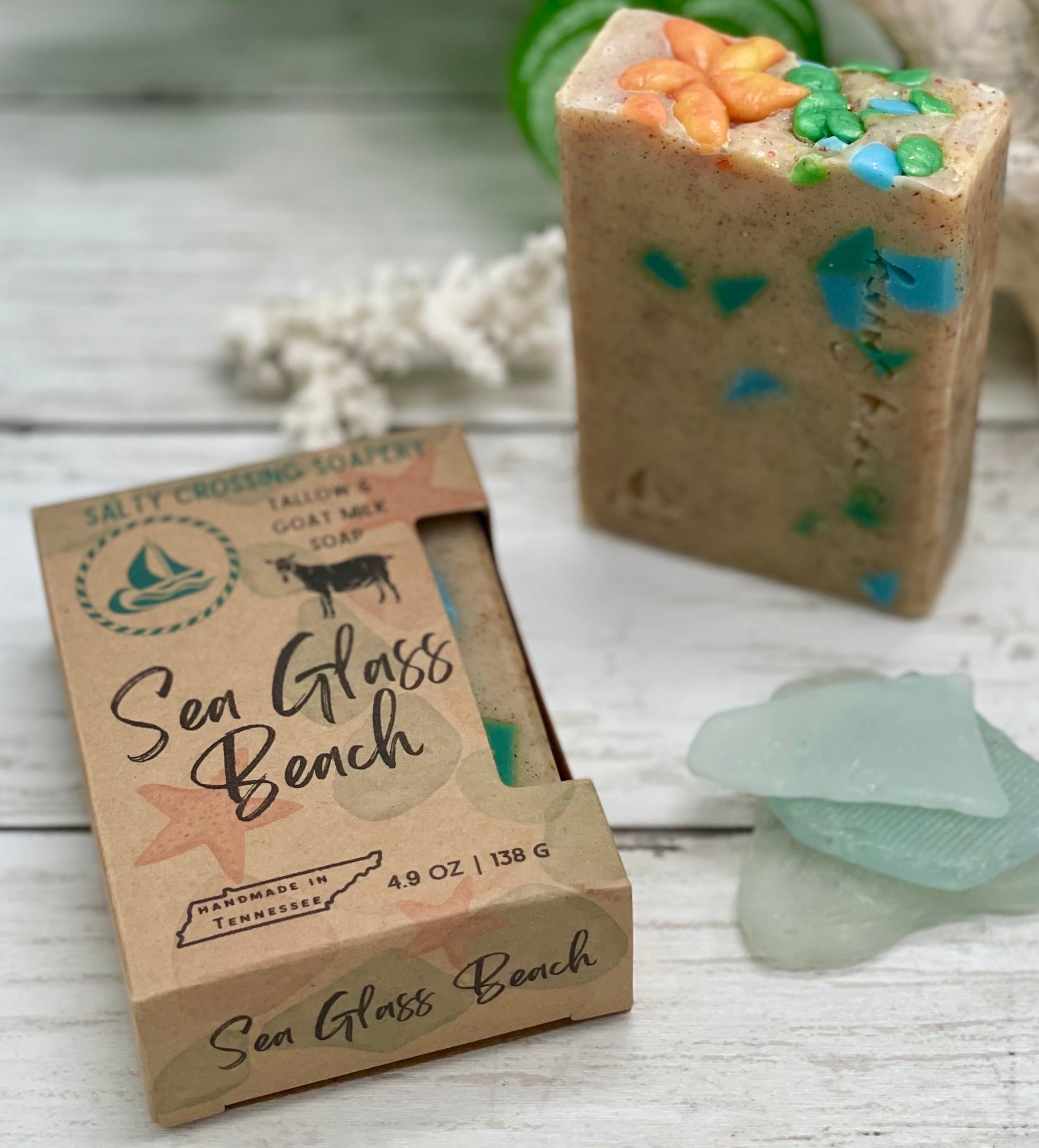 Bar of soap with decorative elements next to its packaging on a wooden surface.