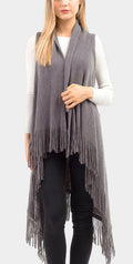 Woman wearing a gray fringe vest over a white sweater on a light gray background