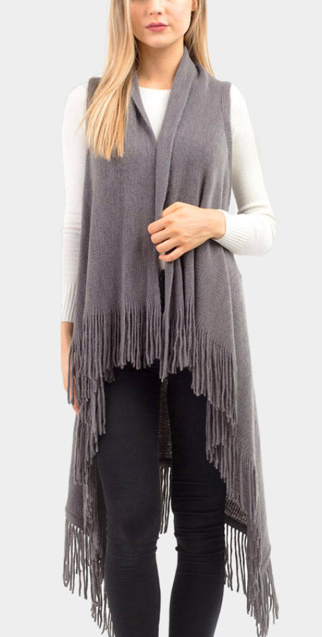 Woman wearing a gray fringe vest over a white sweater on a light gray background